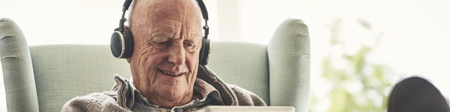 Iäkäs mies kuulokkeet korvillaan.