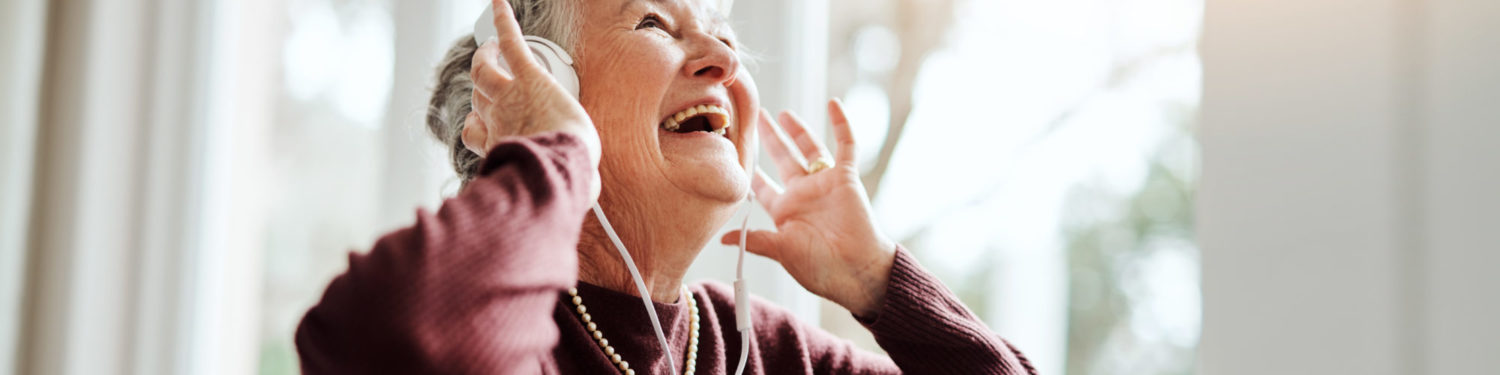 Shot of happy senior woman listening to music with headphones at a retirement home